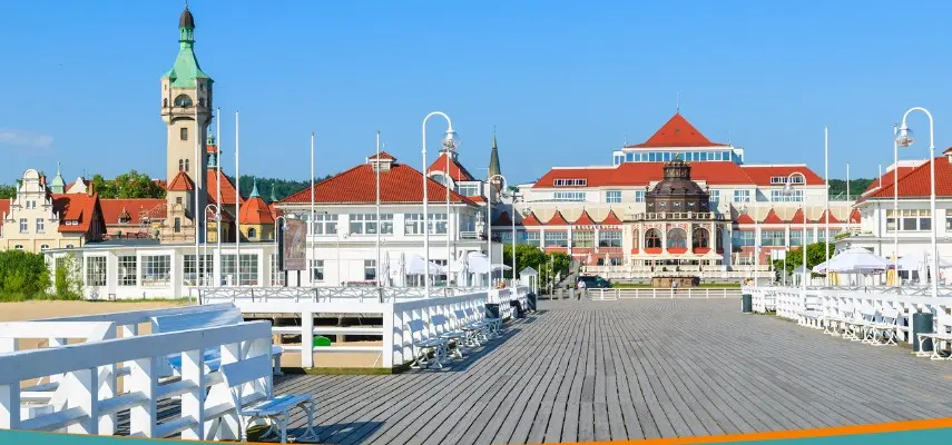 Sopot Pier looking toward Spa Square with the lighthouse, Spa House, and historic resort villas with red roofs