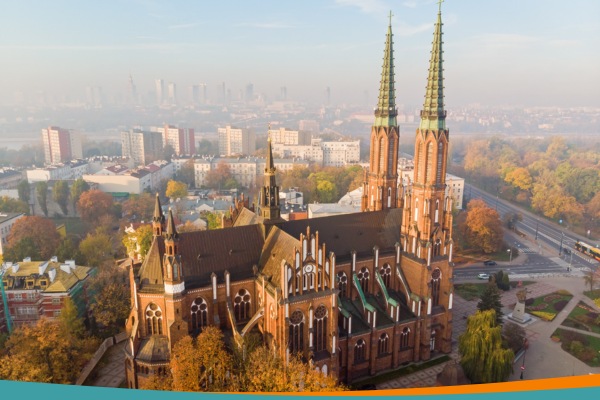 Aerial view of St. Florian's Cathedral in Warsaw's Praga district, with the city centre skyline visible across the Vistula in the background